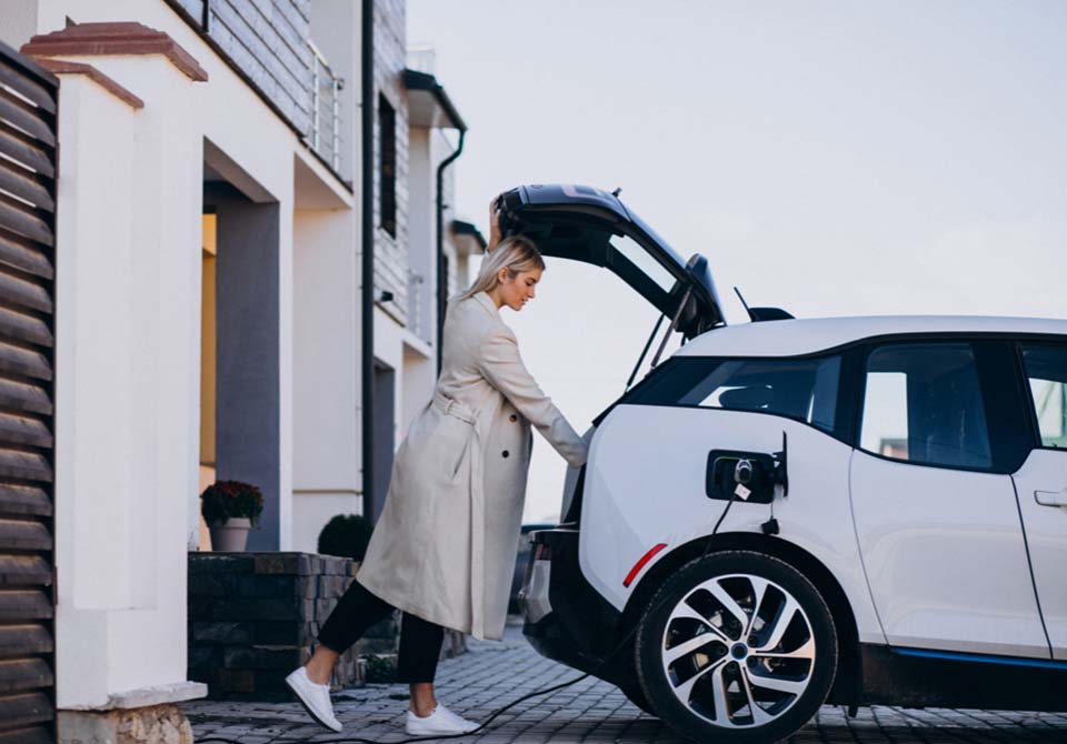 Woman charging an electric car outside her house