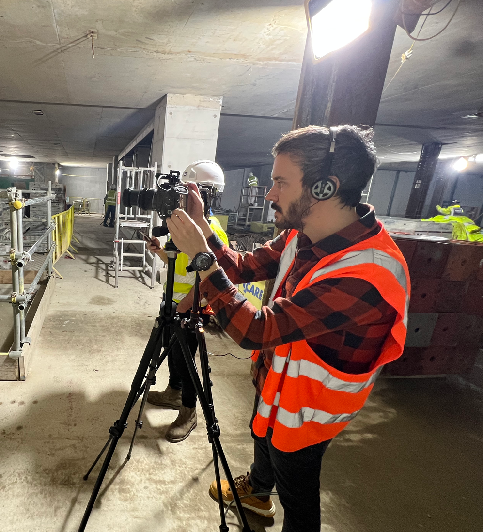 Man wearing an orange safety vest taking a photo on a construction site