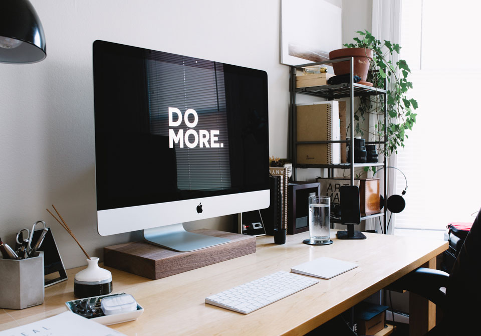 Desktop computer on desk showing 'DO MORE.' message