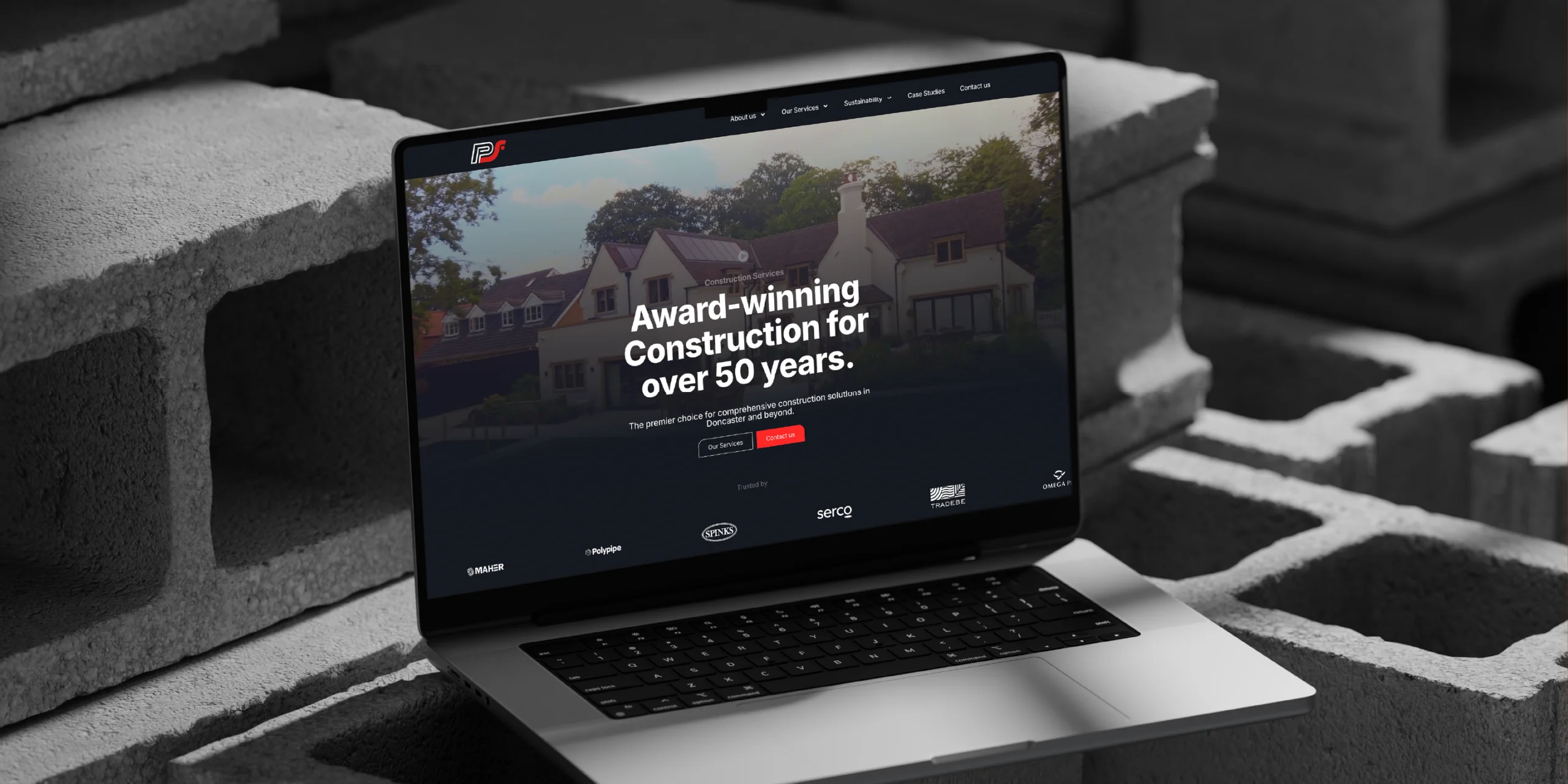 Laptop displaying a construction company's website surrounded by concrete blocks