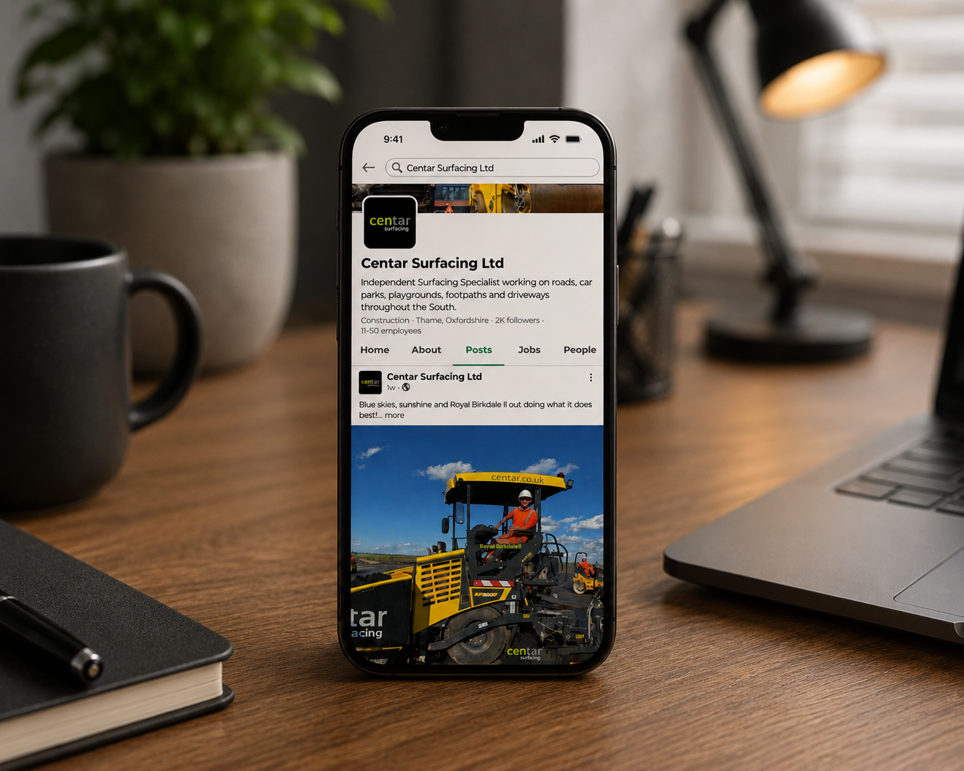 Smartphone displaying Centar Surfacing Ltd social media page on a wooden desk