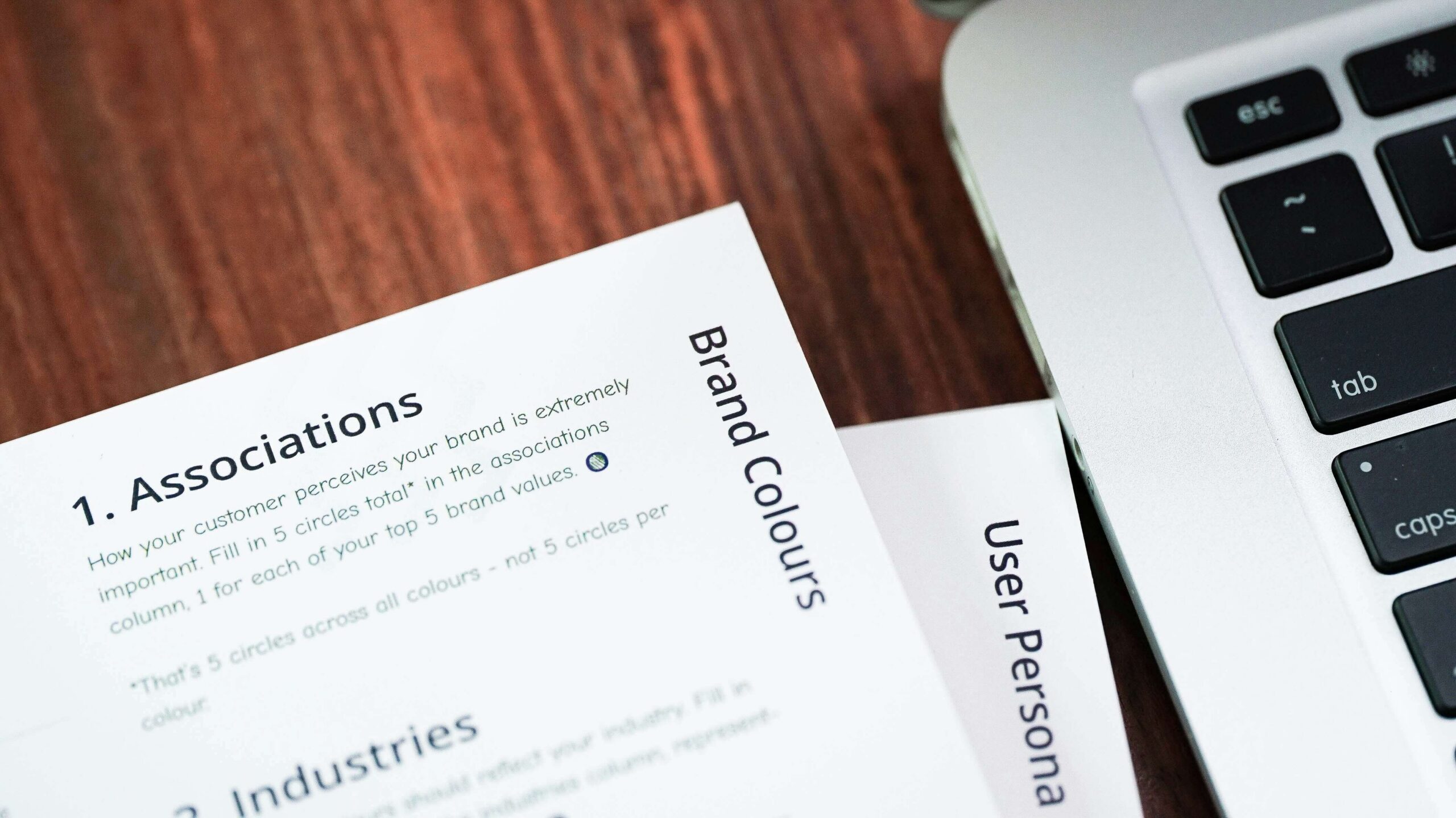 Partial view of a brand strategy report next to a laptop keyboard on a wooden desk