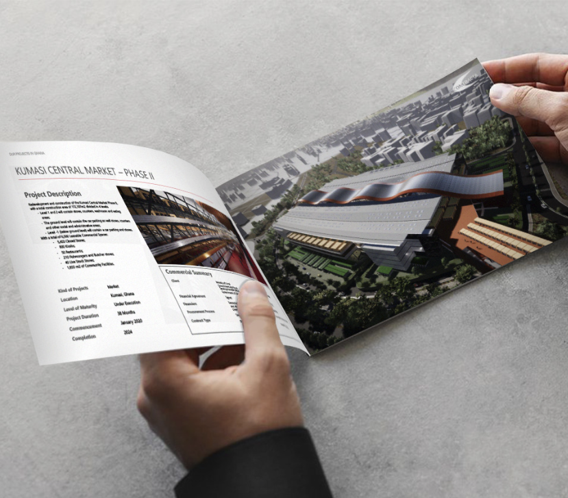 Hands holding an open printed brochure showing a building project and architectural render