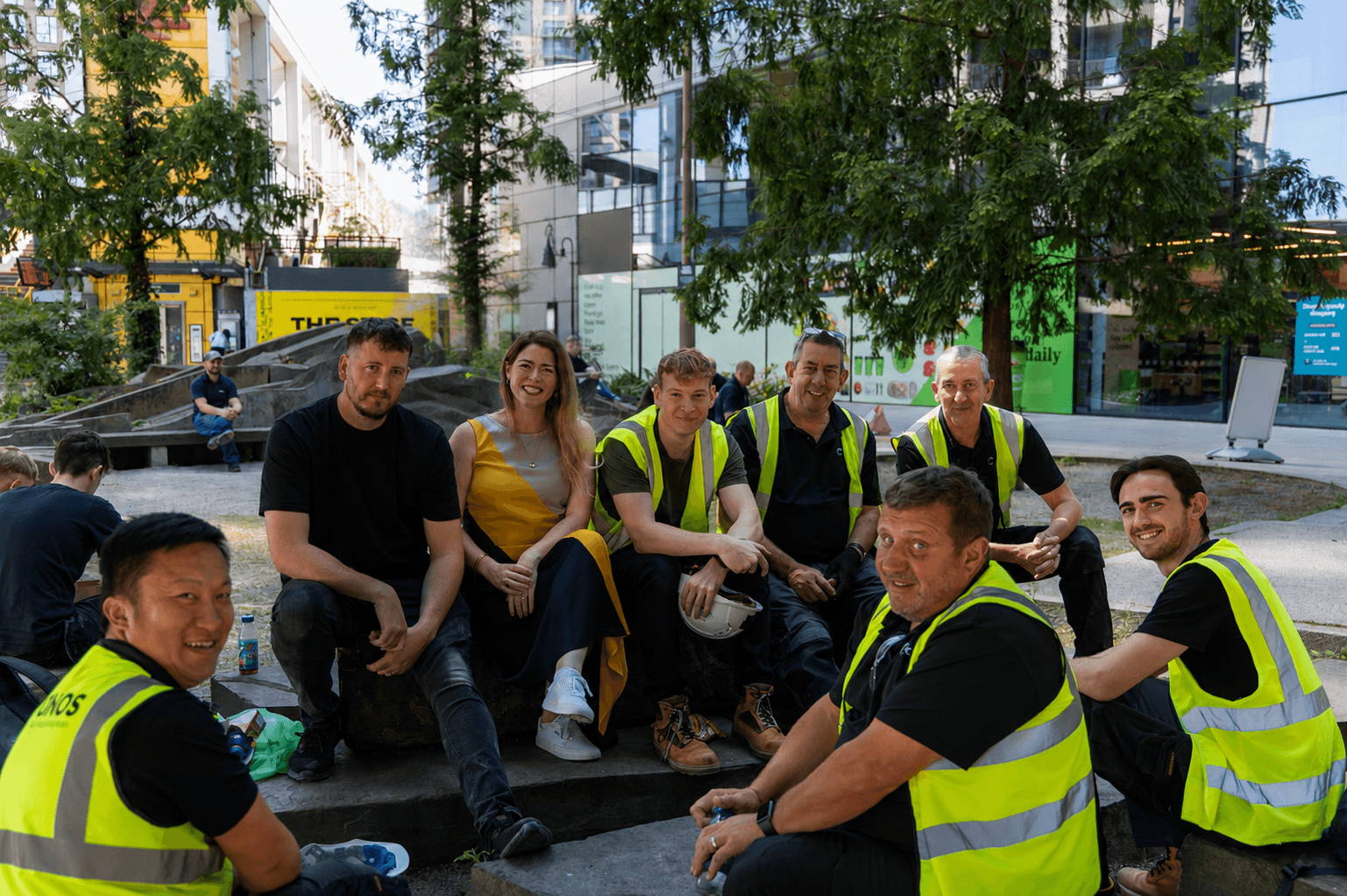 Group of construction workers and a woman sitting outdoors in a city park area
