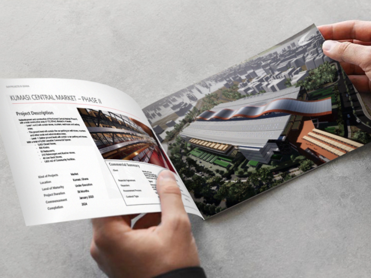 Hands holding a brochure showing Kumasi Central Market Phase II project details and architectural model