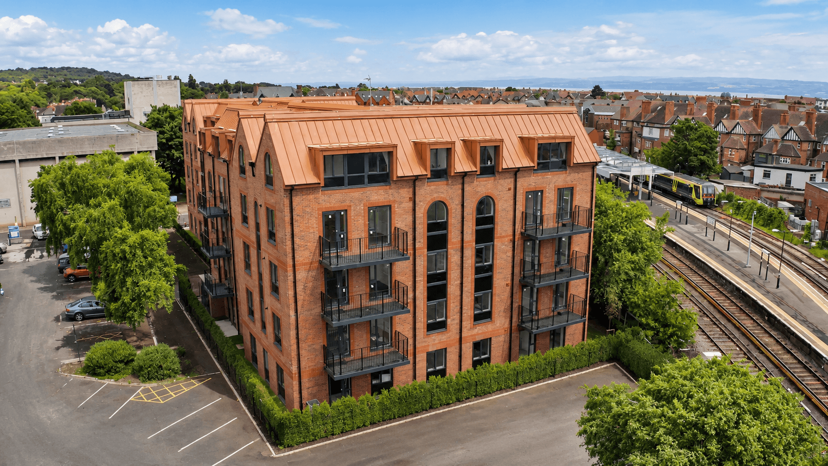 Aerial view of a modern brick apartment building near a train station